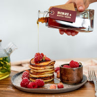 BIRZĪ meadowsweet syrup poured over pancakes and raspberries